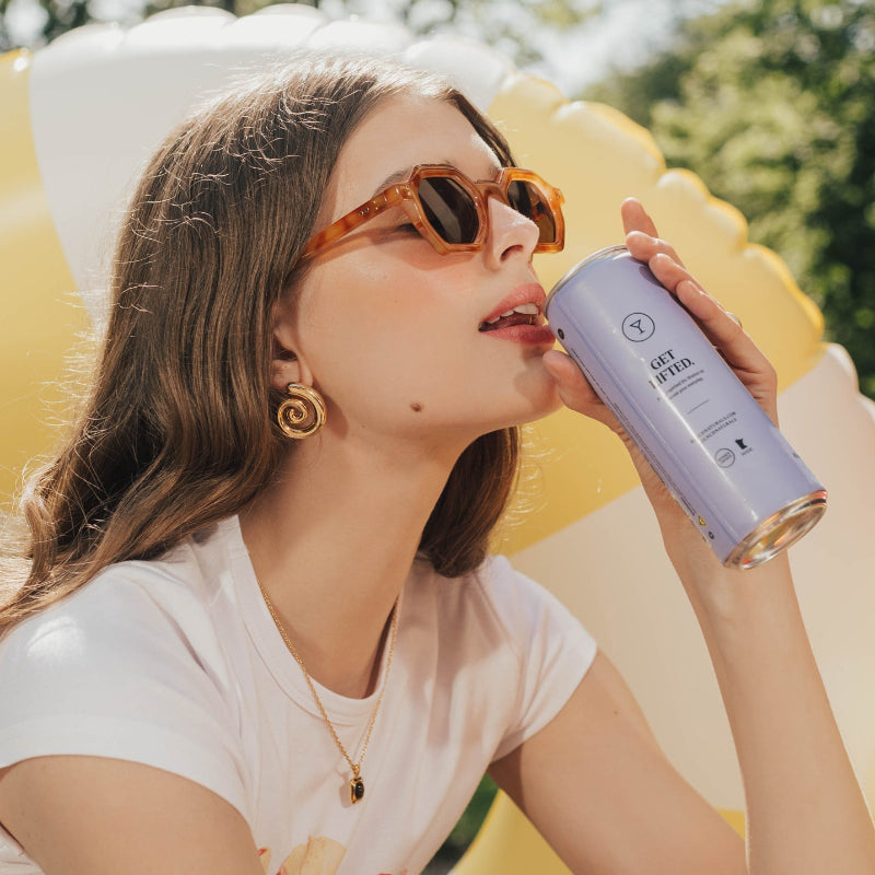 Woman drinking from a can with a colorful background at Sèchey