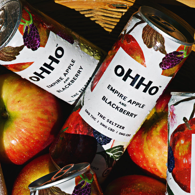 OHHO Empire Apple and Blackberry THC Seltzer cans with apples and blackberries in the foreground.