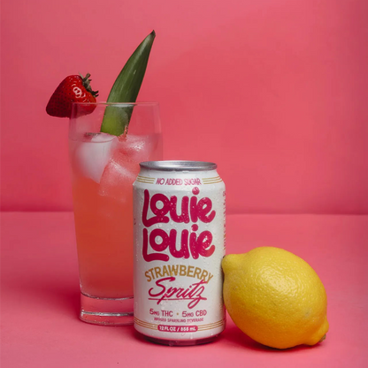 Louie Louie Strawberry Spritz can with a glass of strawberry lemonade and a lemon on a pink background